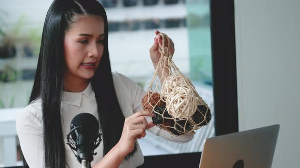 Woman sell product online in front of laptop and microphone, she look expert for selling