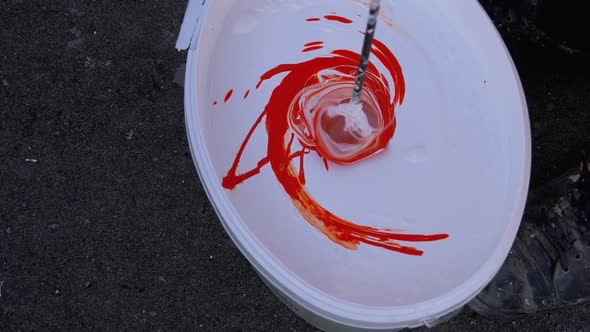 Mixing White with Red Paint in the Bucket Using Whisk on a Drill. Slow Motion