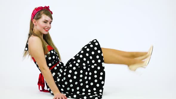 A Beautiful 50s Pin-up Girl Sits on the Floor, Smiles at the Camera and Moves in Rhythm of Music
