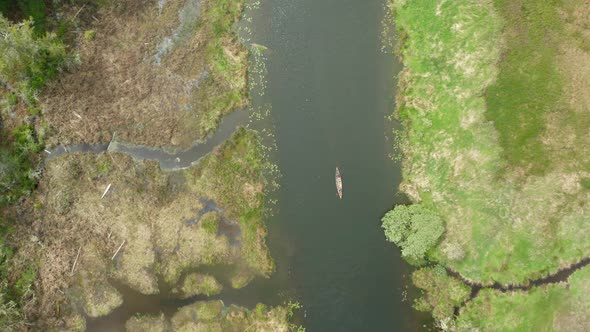 High altitude drone shot of a canoe being paddled through an estuary