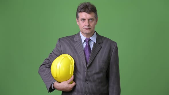 Mature Handsome Businessman Against Green Background