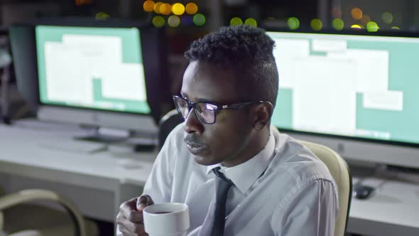 African Businessman Working at Night and Drinking Coffee