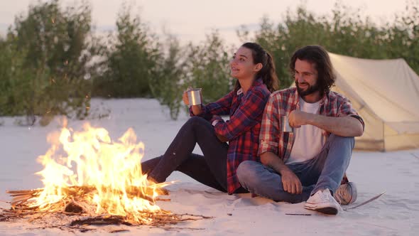 Tourist Couple Camping Near Campfire Outdoors on the Nature