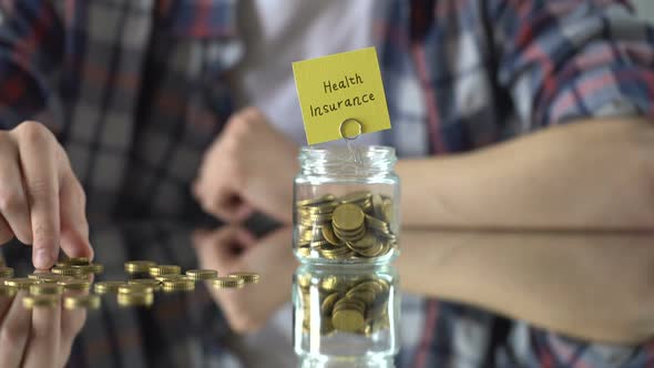 Health Insurance Phrase Written Above Glass Jar With Money, Savings Concept