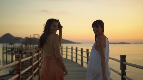 Two Young Women Dressed in the Evening Dress Walking Pier During Sunset on Their Vocation They