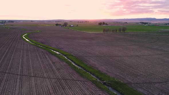 Flying over small canal cutting through farmers field in Idaho