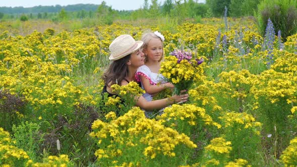 Happy Woman with Daughter Looking at Wildflowers