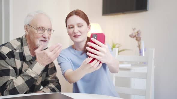 A Woman Teaches Her Grandfather How to Take a Selfie on the Phone