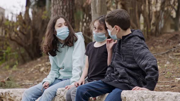 Coronavirus pandemic - kids wearing face masks to avoid contagion sitting bored