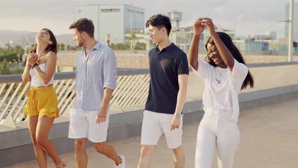 Laughing Multiethnic Best Friends Enjoying Summertime While Walking on Embankment