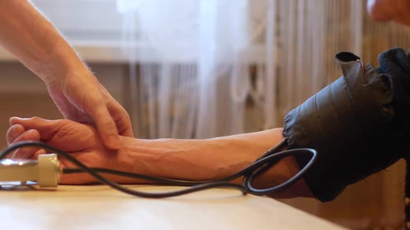 At home, an elderly person's blood pressure is measured with a tonometer.