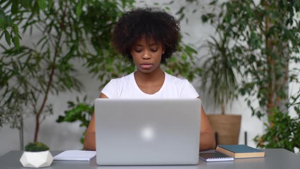 Portrait of Young African Woman College Student Thinking Typing on Laptop Writing Text Notes in