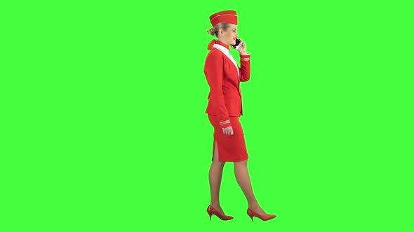 Stewardess Speaks on the Phone and Paces Into the Distance. Green Screen. Side View