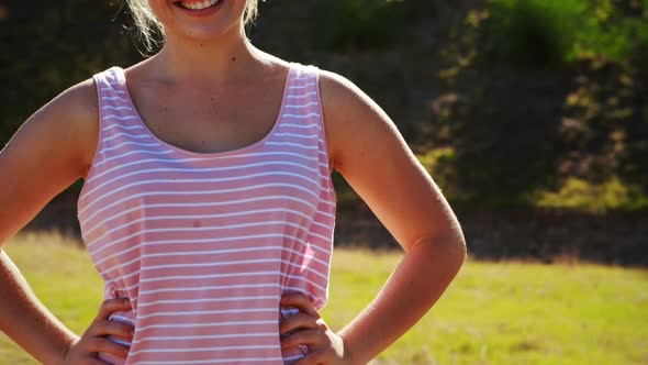 Portrait of happy woman standing with hands on hip during obstacle course