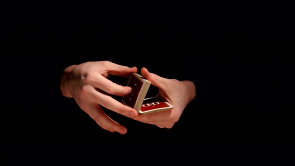 Magician`s Hands Making Trick with Playing Cards on Black Background