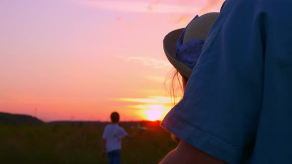 A Happy Family Spend Time Together at Sunset in the Backyard Mom Stands in an Embrace with Her