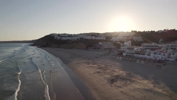 Panoramic aerial view looking at the sunsetting in Praia da Salema beach Algarve Portugal.