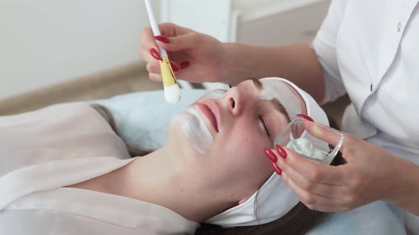 Cosmetologist Applies Clay Mask with Spatula on Face of Woman