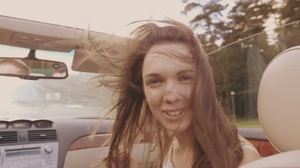 Young beautiful and smiling hipster girl in convertible car