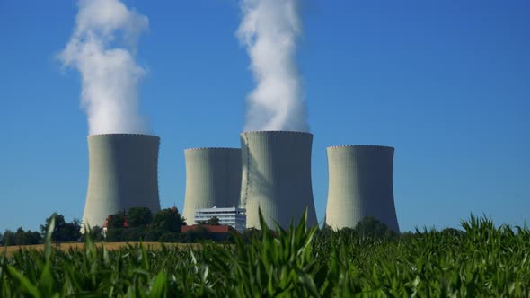 Factory (Nuclear Power Station) - Buildings and Smoke From Chimney - Field with Plants and Blue Sky