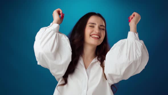 Young Smiling Delighted Woman Dancing Against Blue Studio Background
