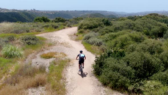 Aerial View of Riding Mountain Bike in a Small Singletrack Dry Trail in the Mountain. alt