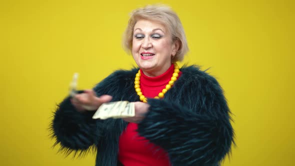 Portrait of Rich Senior Woman in Fur Coat Scattering Money in Slow Motion
