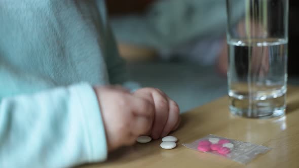 Close-up of children's hands taking pills from a bedside table