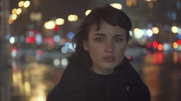 Melancholic Emotive Caucasian Female Standing Staring at You In The City At Night While It Rains