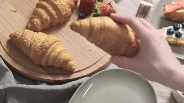 Top Down View Woman Hand Take One of Three Delicious Croissants That are on Plate and is About to