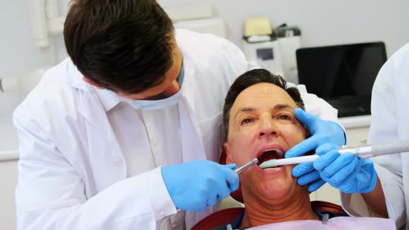 Dentists examining a male patient with tools