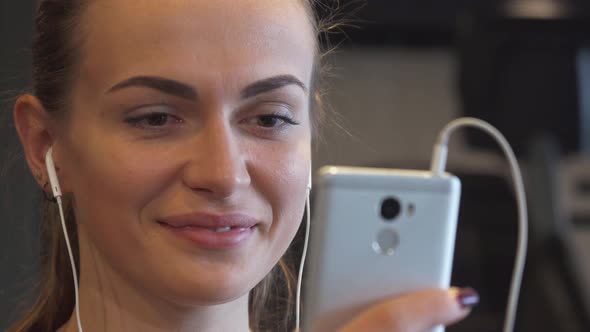 Close-up of a Smiling Girl Face That Switches Something in the Phone