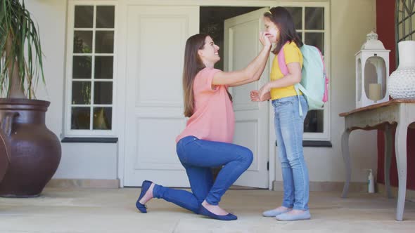 Caucasian mother putting on face mask and hugging her daughter outside of the house