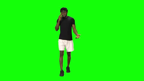 African American Man Is Walking and Talking on the Mobile Phone at Green Screen, Chroma Key. Front