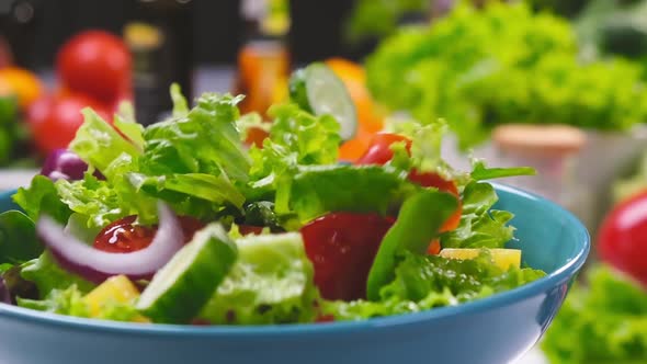 Fresh salad with lettuce leaves and tomato falling into bowl