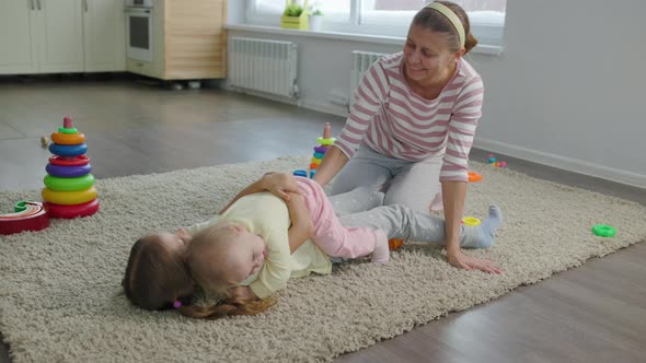 Woman Mother Plays With Two Children Girls Toys In The Room