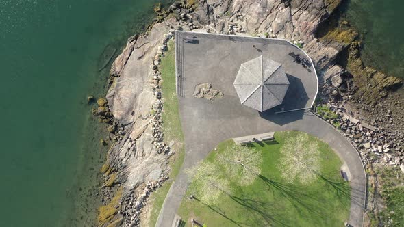 a top down view of a paved platform on top of rocks, on the water on a sunny day. The camera boom do