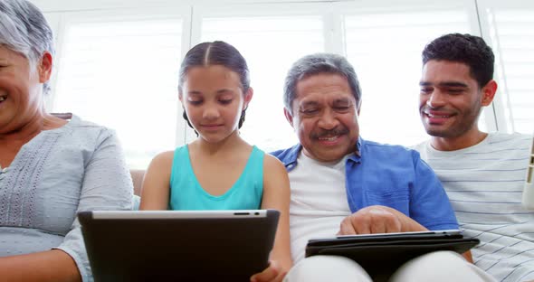 Happy family sitting on sofa and using laptop, mobile phone and digital tablet