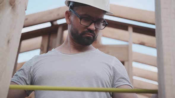 Man in a Construction Helmet Taking Measurements at Construction Site