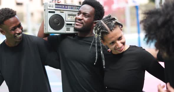 Group of young african people listening music from vintage boombox stereo outdoor