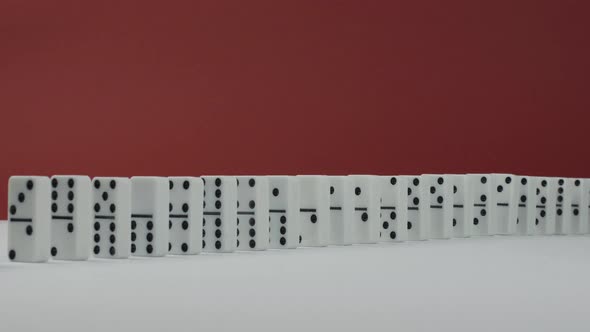Domino Effect - a Series of Dominoes Falling Down the Chain on Red Background