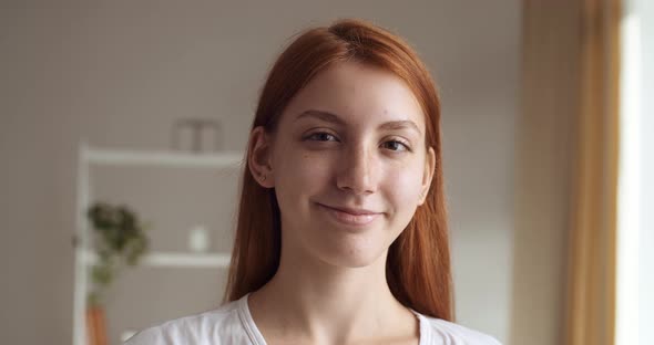 Portrait of Beautiful Young Woman with Red Hair Wearing White Clothes, Looking To Camera and Smiling