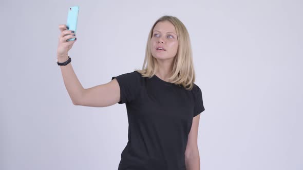 Young Happy Blonde Woman Taking Selfie with Phone