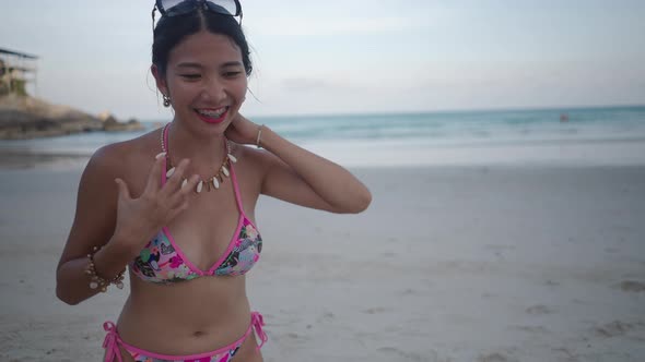 Thai Girl Live Streamer Show Off Her Necklace to Viewers Wearing a Bikini and Sitting on Sand Beach