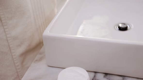 Woman applying moisturizer cream on her face in bathroom