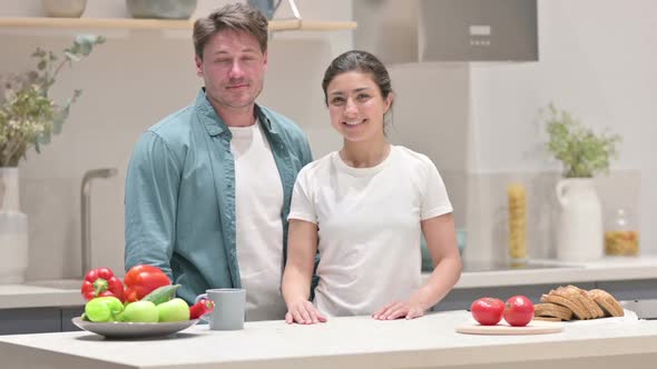 Mixed Race Couple Looking at Camera in Kitchen