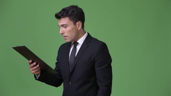 Young Handsome Hispanic Businessman Against Green Background