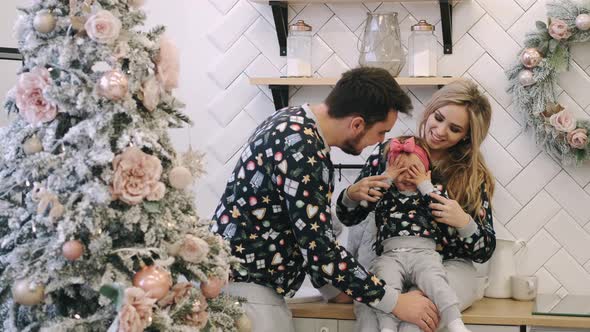 A Young Family in Warm Sweaters with a Baby Daughter in a Christmas Bedroom