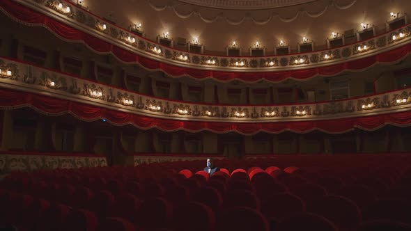 Alone man in theater hall. Rows of empty red cinema chairs in theatre during the period of the covid