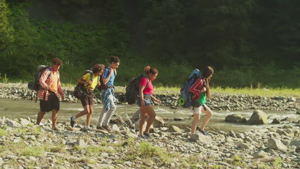 Group of Positive Diverse Multiethnic Backpackers Hiking Near Mountain River